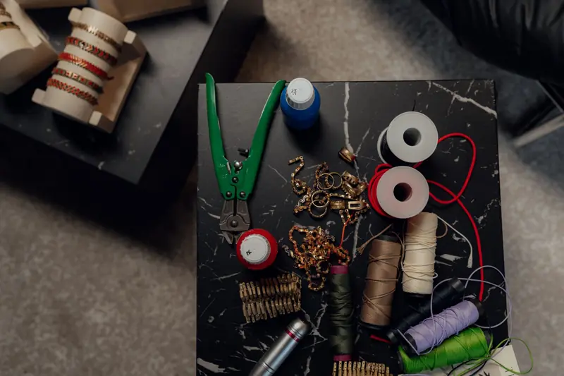 Top view of a crafting table with tools, spools, and jewelry making materials