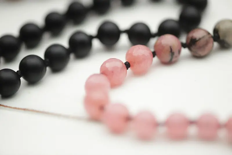 Detailed macro shot of black and pink gemstone bead bracelets on a soft background