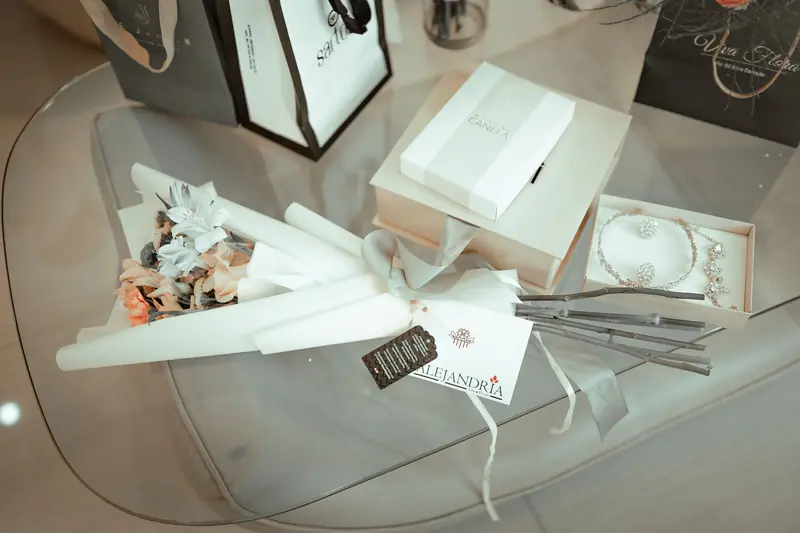 Stylish display of gift boxes, flowers, and jewelry on a glass table