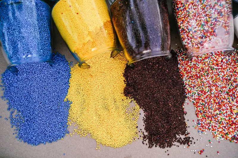 An overhead view of assorted colorful sprinkles and beads spilling from glass jars
