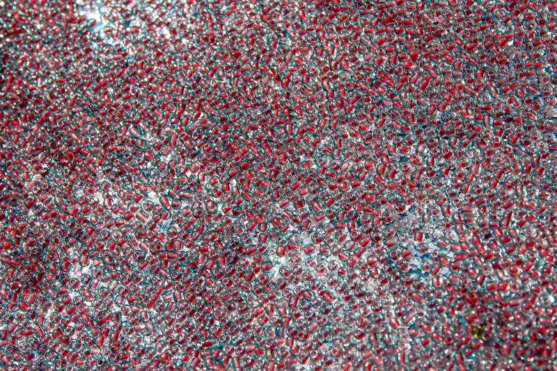 An intricate pattern of red and clear glass beads creating a textured, colorful background