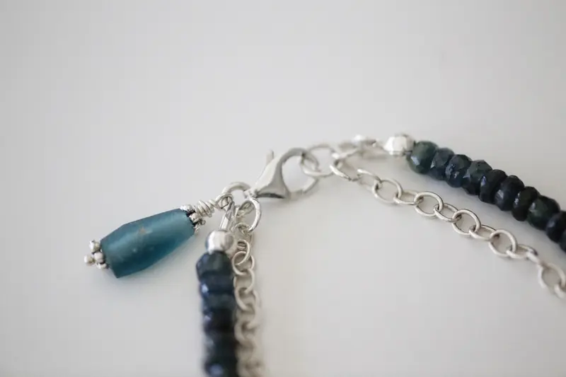 Detailed view of a silver necklace clasp and beaded chain with blue accents