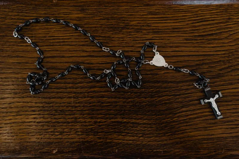 A rosary with black beads and cross on a wooden table
