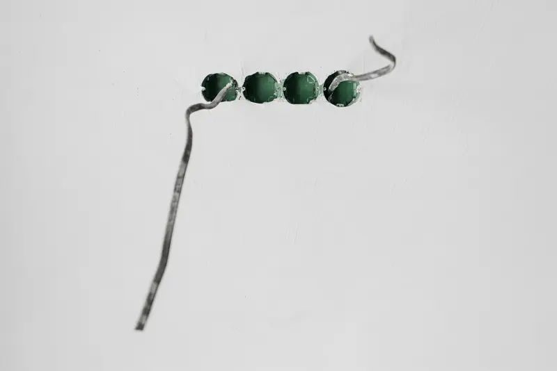 Close-up of green beads on a string against a stark white background
