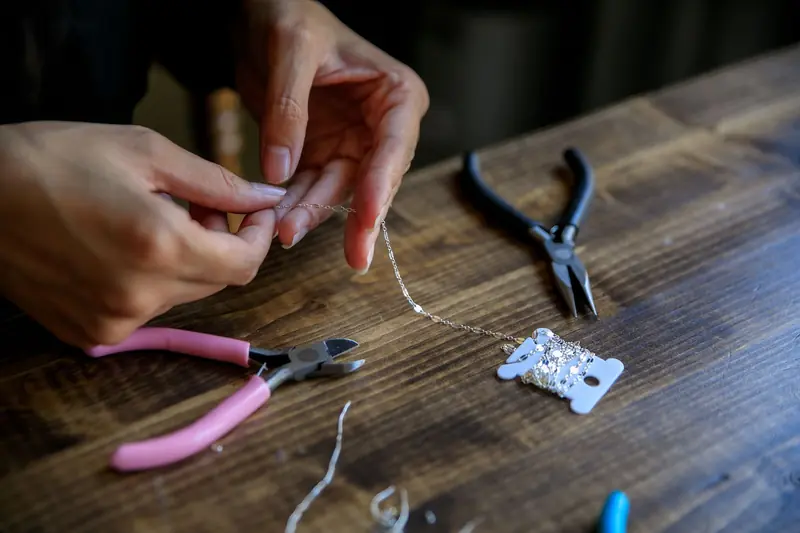 Close-up of hands crafting jewelry with pliers and wire on a wooden table