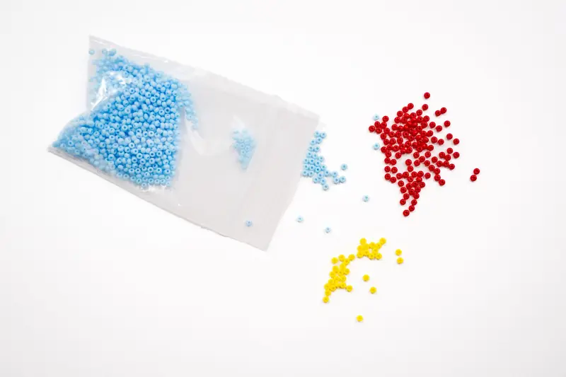 Brightly colored red, yellow, and blue beads scattered on a white backdrop, ideal for crafting and jewelry making