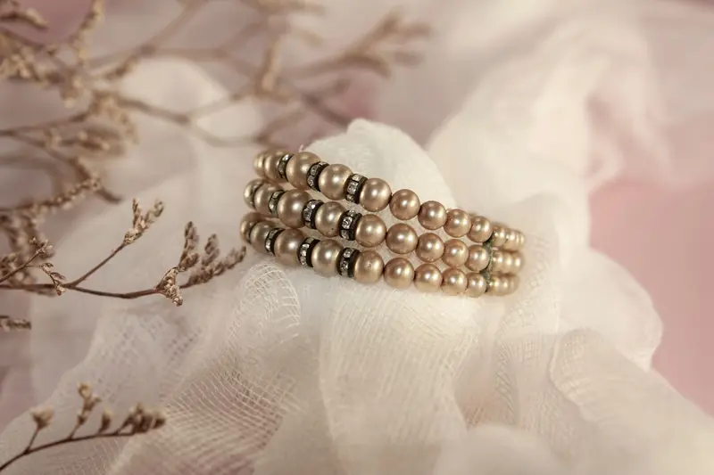 Luxurious pearl bracelet elegantly displayed on a delicate fabric with dried flowers