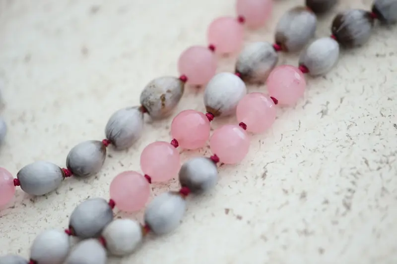 Elegant close-up shot of pink and gray beads forming a stylish necklace on a marble surface
