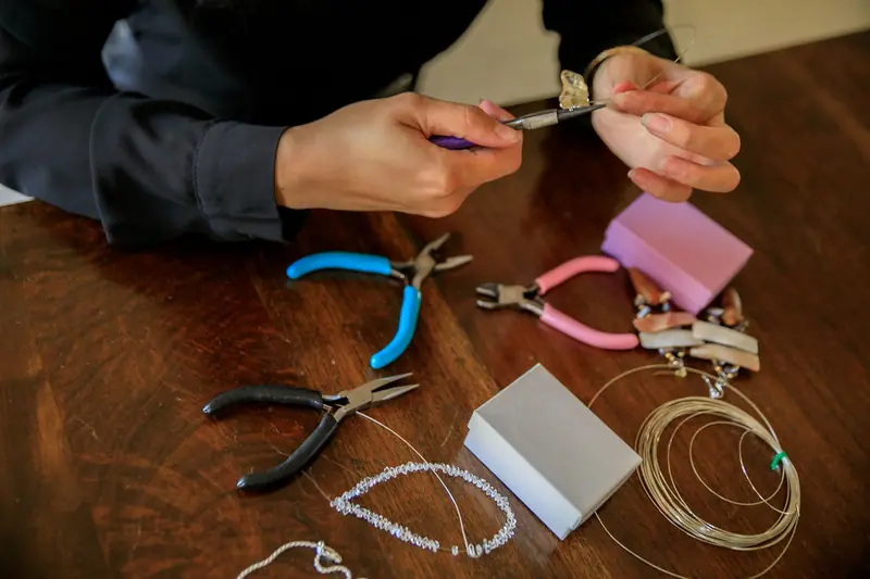 A close-up of hands crafting a necklace using pliers and tools, perfect for DIY jewelry enthusiasts