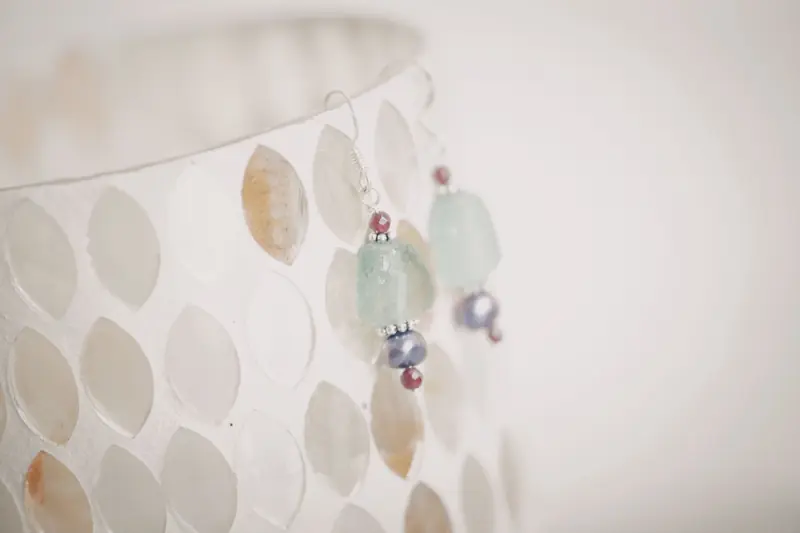 Close-up image of stylish beaded earrings with aquamarine and pearl accents