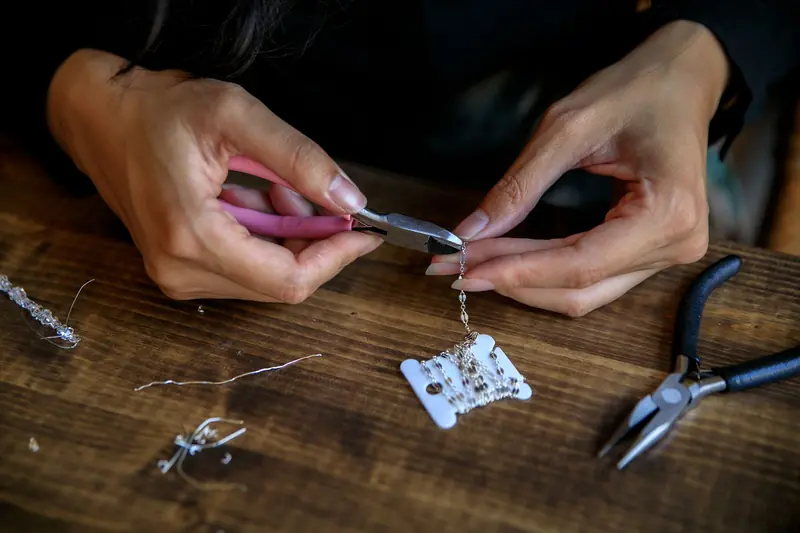 Detailed view of hands crafting jewelry using pliers, showcasing creativity and craftsmanship