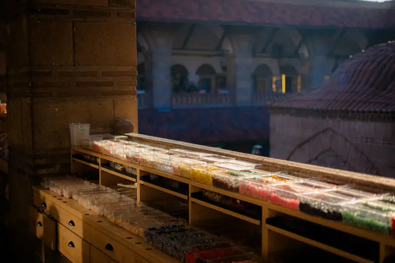 A market stall in a historic building showcasing colorful beads in containers on wooden shelves