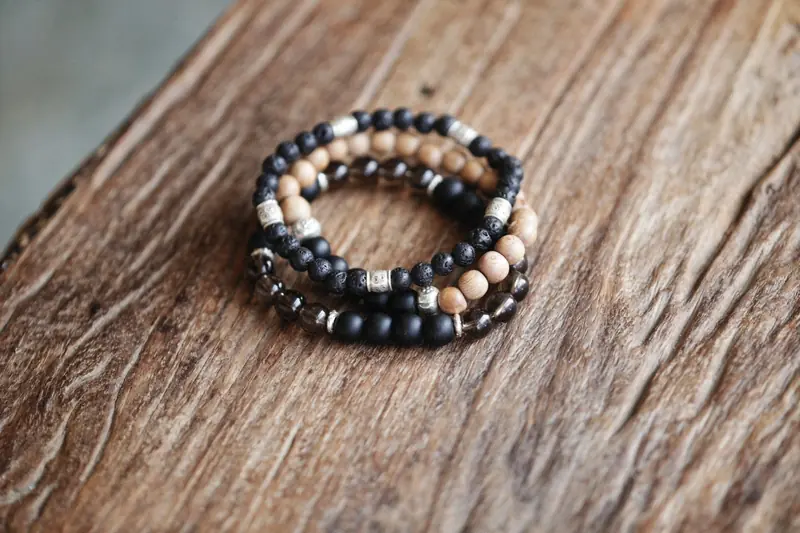 Close-up of beaded bracelets in various colors and textures on a rustic wood surface