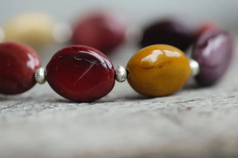 Detailed close-up of a colorful beaded necklace with polished stones on a wooden surface