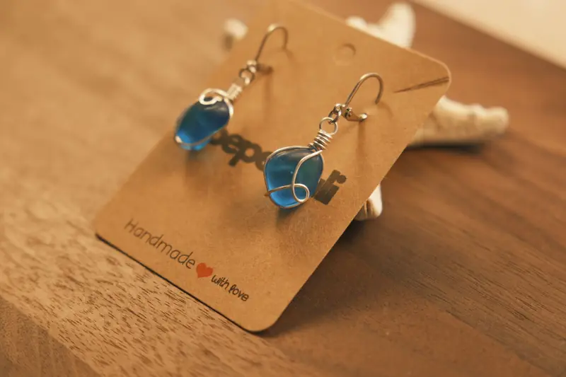 Chic handmade earrings featuring blue stones wrapped in wire on a brown background